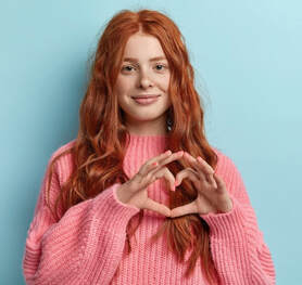 Girl making the love symbol with her hands and smiling as she has found self acceptance